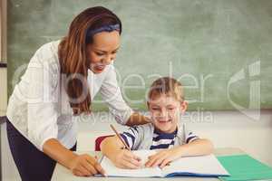 Teacher helping a boy with his homework in classroom