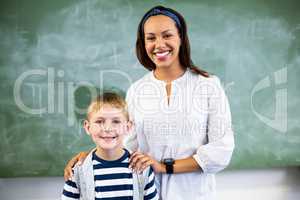 Portrait of smiling teacher and schoolboy standing in classroom