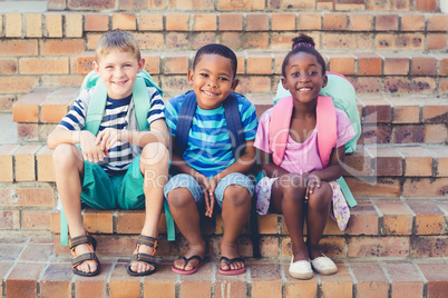 Smiling school kids sitting together on stairs