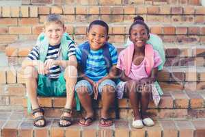 Smiling school kids sitting together on stairs