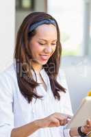 Smiling teacher using digital tablet in classroom