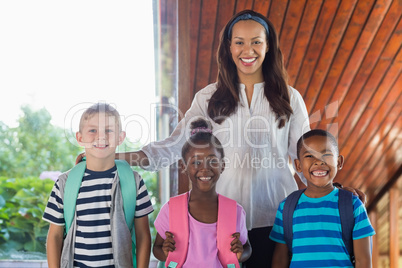 Portrait of smiling teacher and kids standing together with arm around