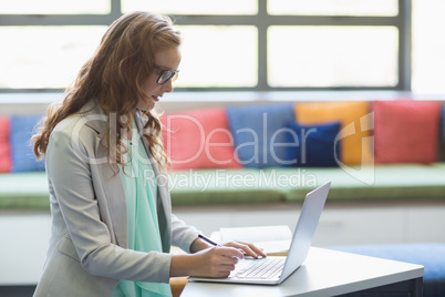 Teacher using laptop in library