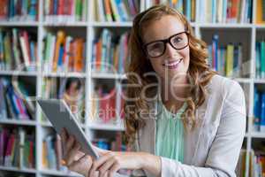 Portrait of smiling using digital tablet in library