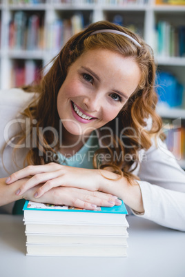 Portrait of smiling school teacher with books in library