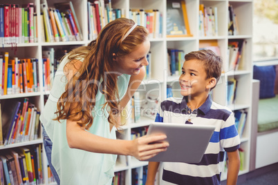 Teacher and school boy using digital tablet in library