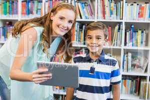 Portrait of teacher and school boy using digital tablet in library