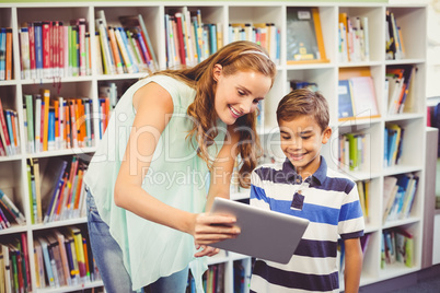 Teacher and school boy using digital tablet in library