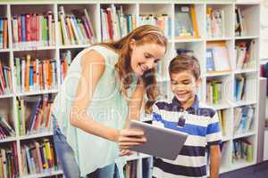 Teacher and school boy using digital tablet in library