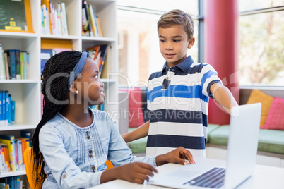 School kids using a laptop in library