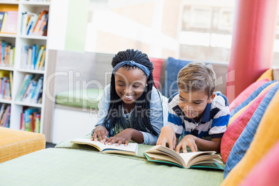 School kids lying on sofa and reading book