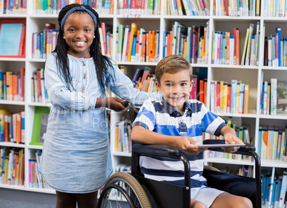 Happy schoolgirl standing with schoolboy on wheelchair