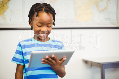 Happy schoolboy using digital tablet in classroom