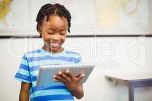 Happy schoolboy using digital tablet in classroom