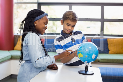 School kids looking at globe in library