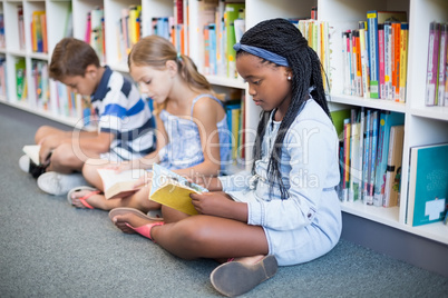 School kids sitting on floor and reading book in library