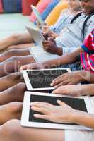 School kids sitting on sofa and using digital tablet in library