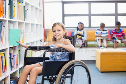 Disabled school girl selecting a book from bookshelf in library