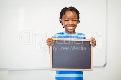 Portrait of smiling school boy holding slate in classroom