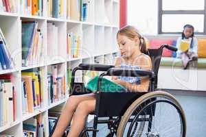 Disabled school girl reading book in library