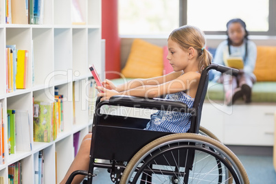 Disabled school girl selecting a book from bookshelf in library