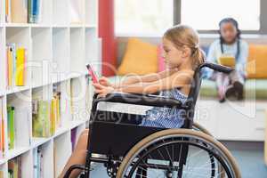 Disabled school girl selecting a book from bookshelf in library