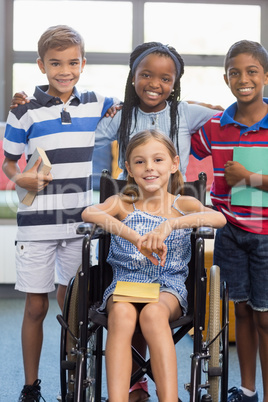 Smiling school kids standing with arm around in library