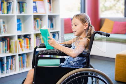 Disabled school girl reading book in library