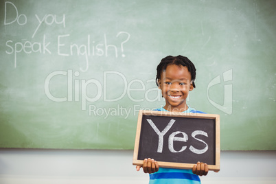 Schoolboy holding a slate in classroom which reads yes