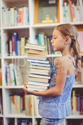 School girl girl holding stack of books in library
