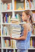 School girl girl holding stack of books in library