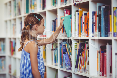 School girl taking a book from bookshelf in library