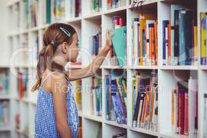 School girl taking a book from bookshelf in library