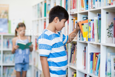 Boy taking a book from bookshelf in library