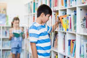 Boy taking a book from bookshelf in library