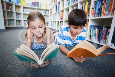 School kids lying on floor and reading a book in library