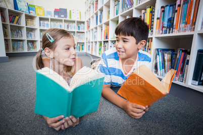 School kids lying on floor and reading a book in library