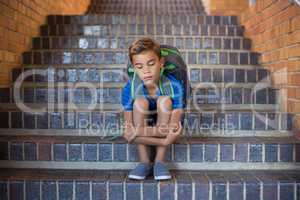 Sad schoolboy sitting alone in staircase