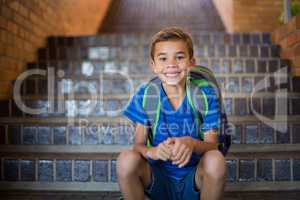 Smiling schoolboy sitting on staircase