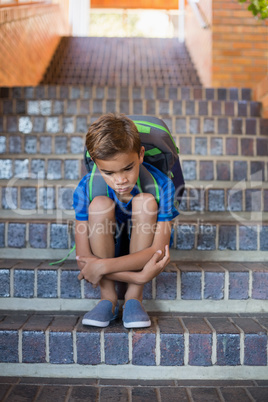 Sad schoolboy sitting alone on staircase