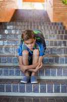 Sad schoolboy sitting alone on staircase