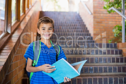 Schoolboy holding a book on staircase