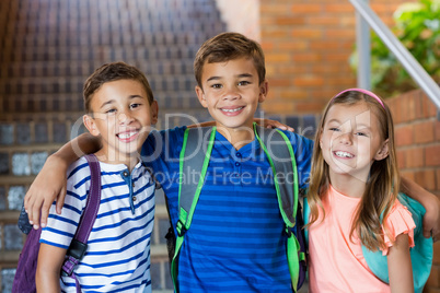 Smiling school kids standing with arm around