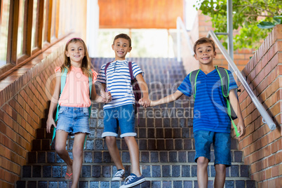 Happy school kids holding hands and walking on staircase