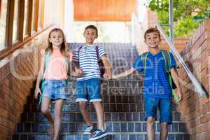 Happy school kids holding hands and walking on staircase
