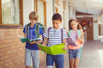 School kids reading books while walking in corridor