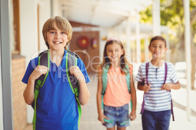 Smiling school kids standing in school corridor