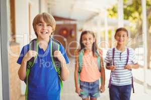 Smiling school kids standing in school corridor