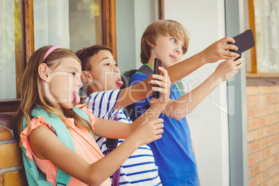 School kids taking selfie with mobile phone in corridor