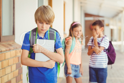 School friends bullying a sad boy in corridor